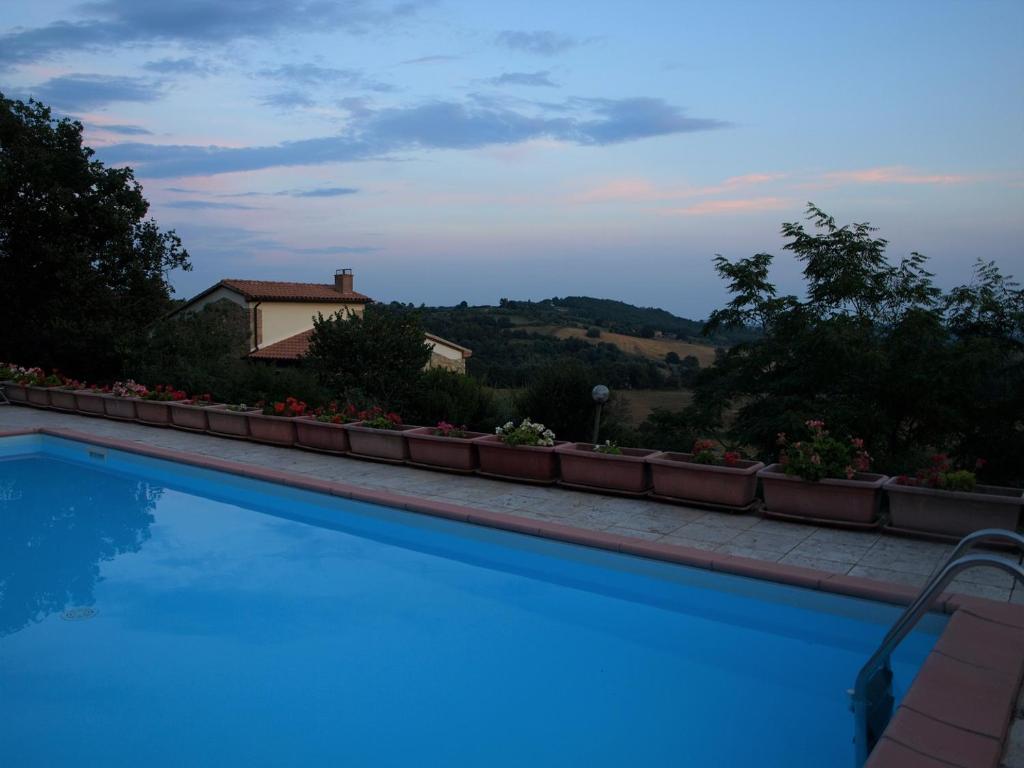 a blue swimming pool with a house in the background at Agriturismo Podere 3 Querce in Manciano