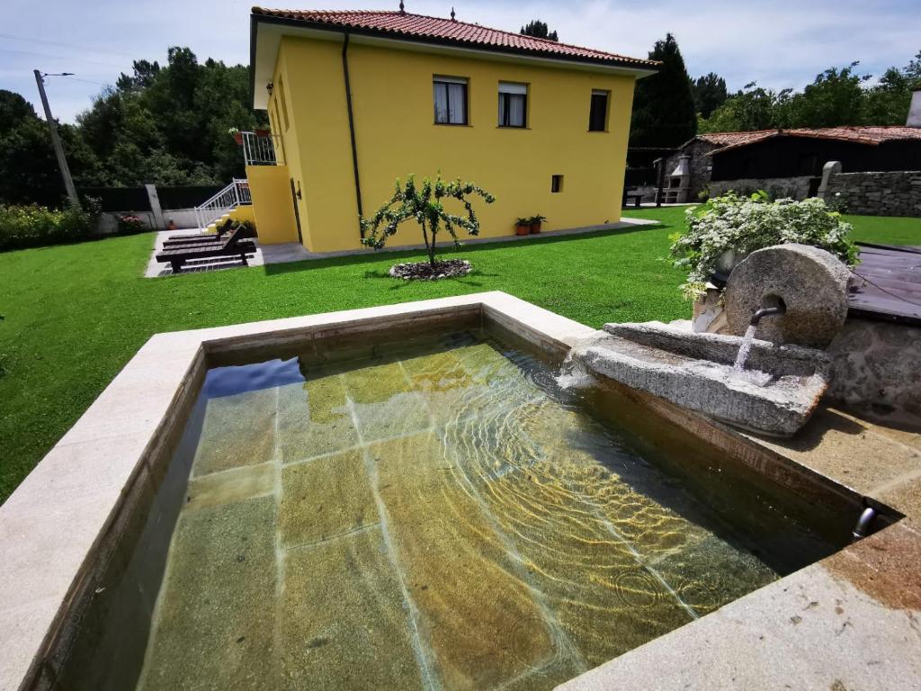 una fuente de agua en un patio con una casa en A Maquia Do Pousavedra, en Sober