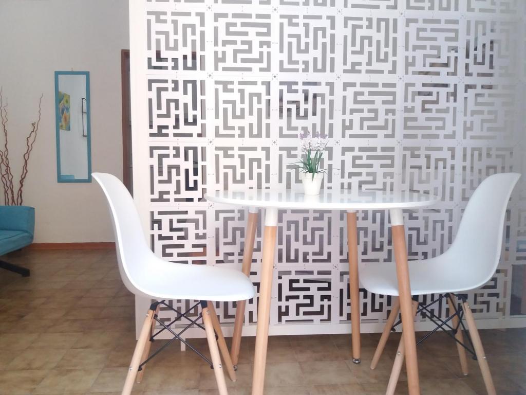 einen Esstisch mit weißen Stühlen und einer Wand in der Unterkunft Casa Vacanze Mazzini in Santa Maria al Bagno