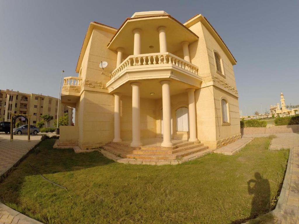 a large yellow house with a balcony on the grass at فيلا للايجار في الساحل الشمالي in Dawwār ‘Abd al ‘Aţī Abū ‘Ajūz