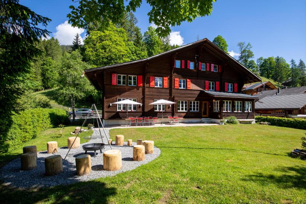 una gran casa de madera con un jardín delante de ella en Naturfreunde Hostel Grindelwald en Grindelwald