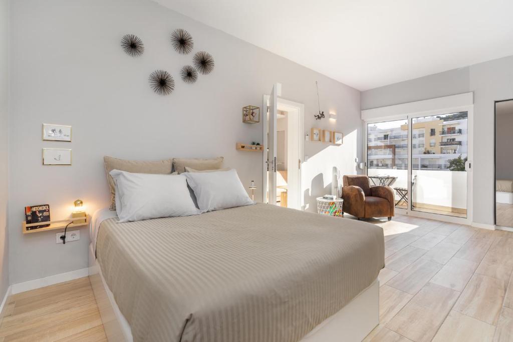 a white bedroom with a large bed and a chair at Natural Grey Albufeira in Albufeira