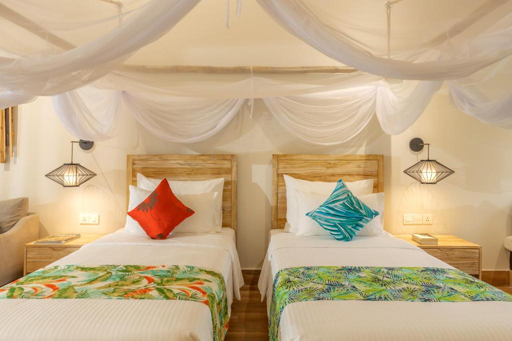 a bedroom with two beds with colorful pillows at Pax Ana Doc Let Resort & Spa in Ninh Hòa