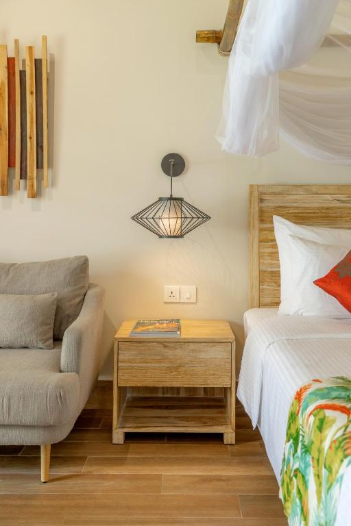 a bedroom with a bed and a chair and a table at Pax Ana Doc Let Resort & Spa in Ninh Hòa