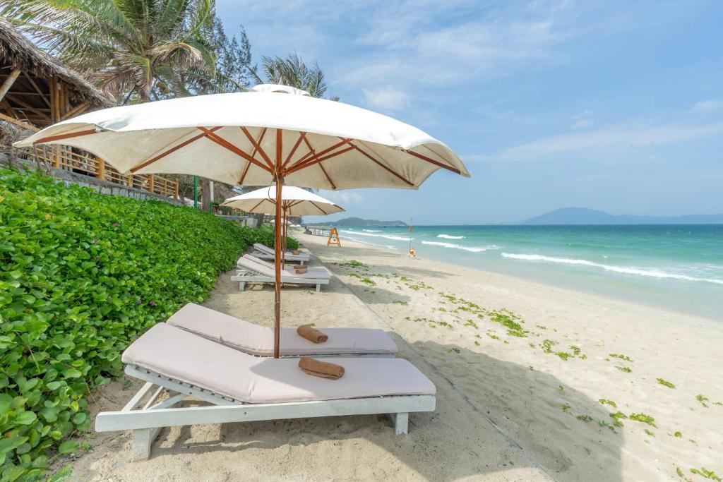 a beach with two lounge chairs and an umbrella at Pax Ana Doc Let Resort & Spa in Ninh Hòa