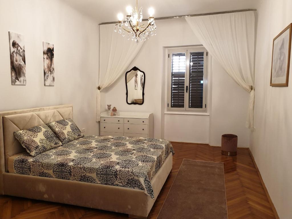 a bedroom with a bed and a chandelier at RoyalGuest Apartment in Koper