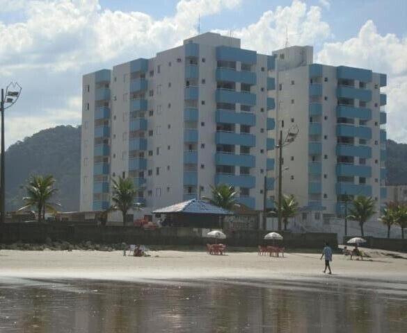 una persona caminando por la playa cerca de un gran edificio en Edifício Santorini en Mongaguá