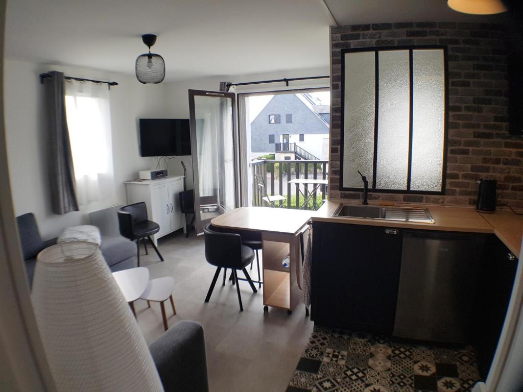 une cuisine et un salon avec une table et des chaises dans l'établissement Le COCON CABOURGEAIS, à Cabourg