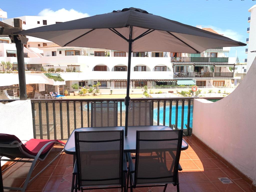 una mesa y sillas bajo una sombrilla en el balcón en Apartment Parque Royale 1, en Adeje