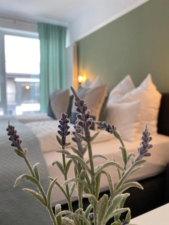 Holiday House Rasnov في ريسنوف: مزهرية مع الزهور الأرجوانية أمام السرير