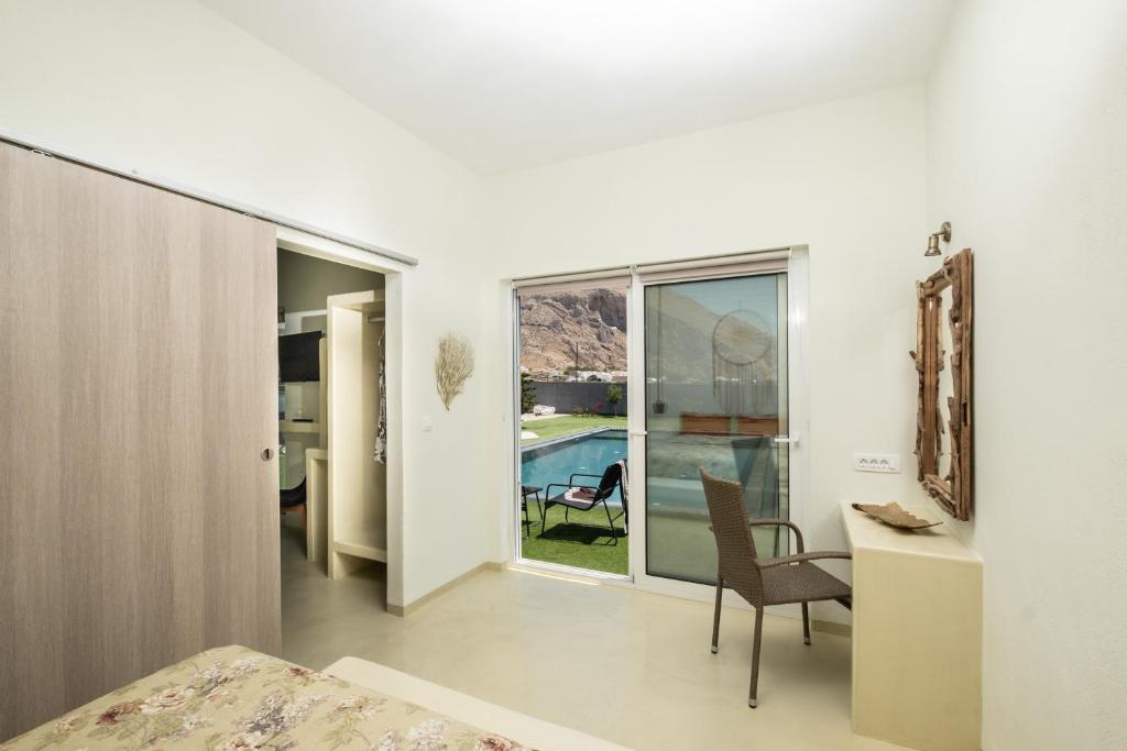 una camera da letto con scrivania, sedia e finestra di Sagma Villas a Perissa
