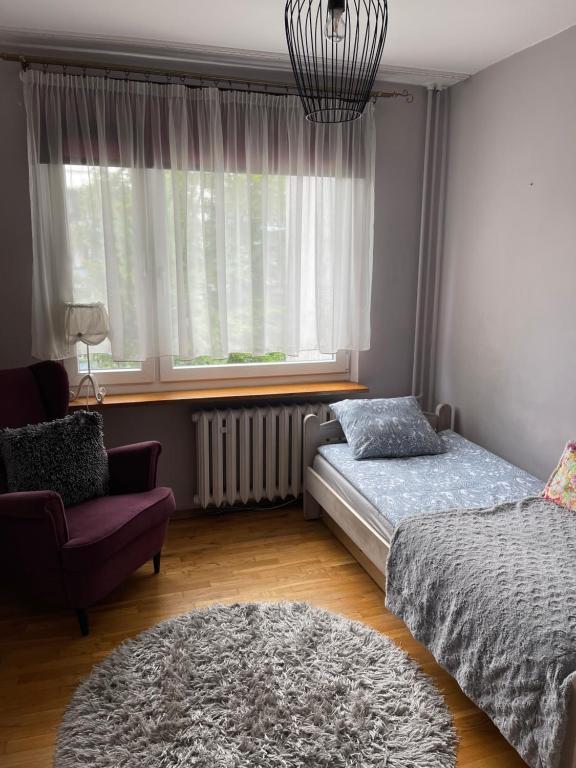 1 dormitorio con 2 camas, silla y ventana en Apartament Siewna-moje miejsce na idealne wakacje, en Cracovia