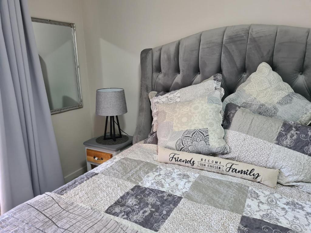 a bedroom with a bed with a gray headboard and pillows at Royal Apartments Kimberley in Kimberley