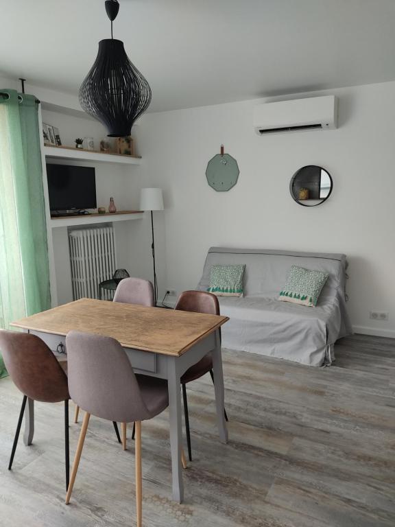 un salon avec une table et des chaises et un lit dans l'établissement Appartement climatisé avec balcon,wifi, proche remparts, à Avignon