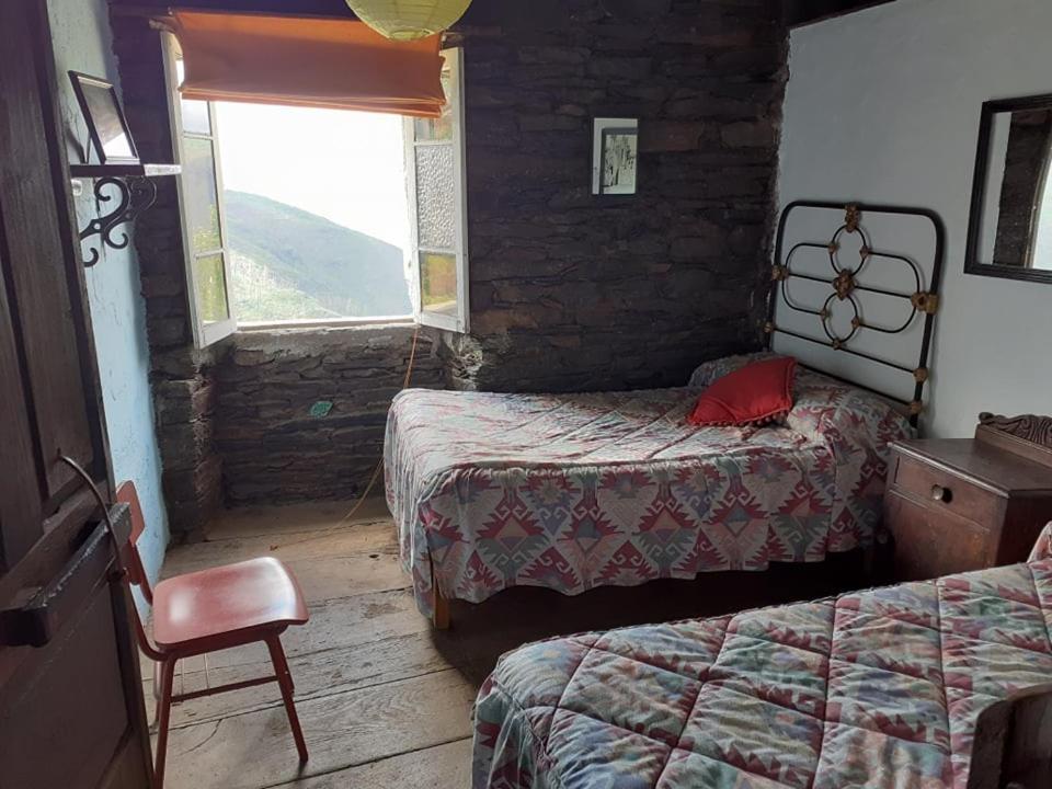 1 dormitorio con 2 camas, silla y ventana en Albergue ESCANLAR en Lugo