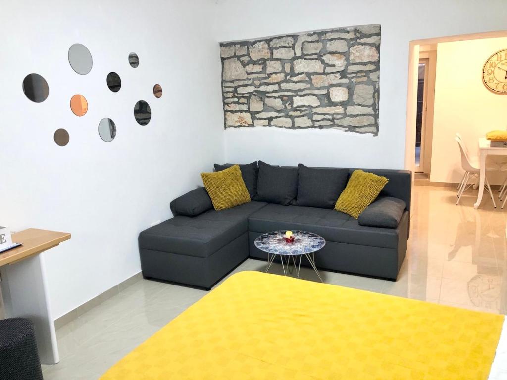 a living room with a blue couch and yellow pillows at Apartments Eni & Dani in Pula