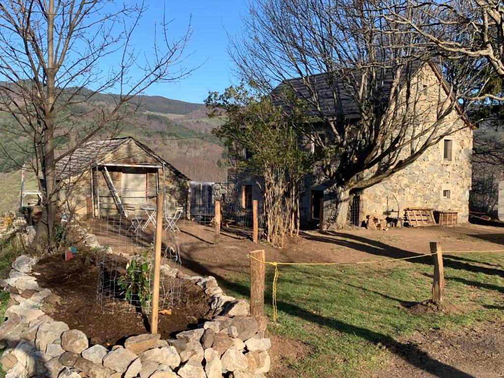 une ancienne grange en pierre avec une clôture et quelques animaux dans l'établissement Gîte de charme en plein cœur de l’Ardèche verte, à La Rochette
