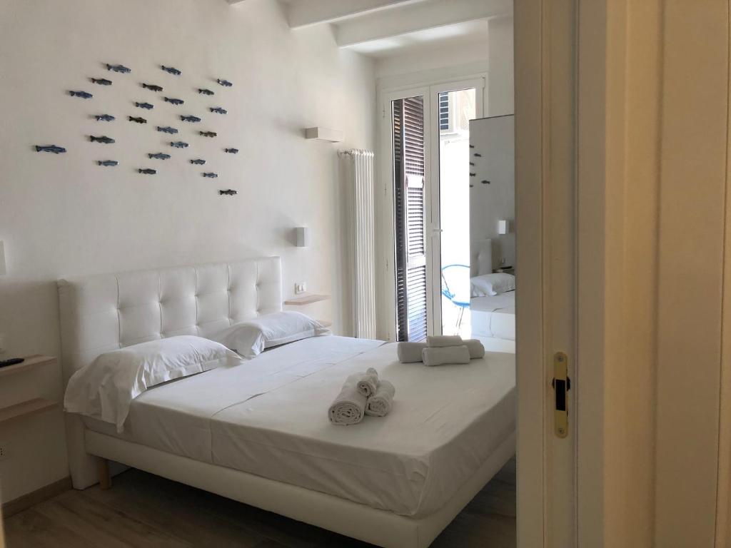 a white bedroom with a large white bed with shoes on it at PORTOROSSO Rooms in Vernazza