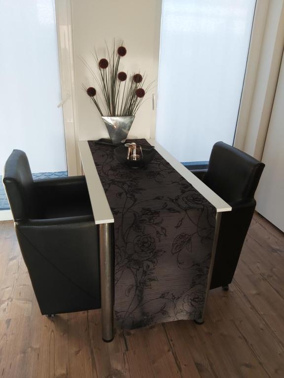 einen Tisch und einen Stuhl mit einer Blumenvase in der Unterkunft Ferienwohnung Auszeit Im Haag in Losheim