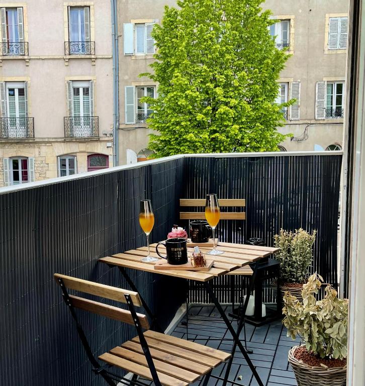 a table and two chairs on a balcony with wine glasses at Appart&amp;Spa Devosge in Dijon