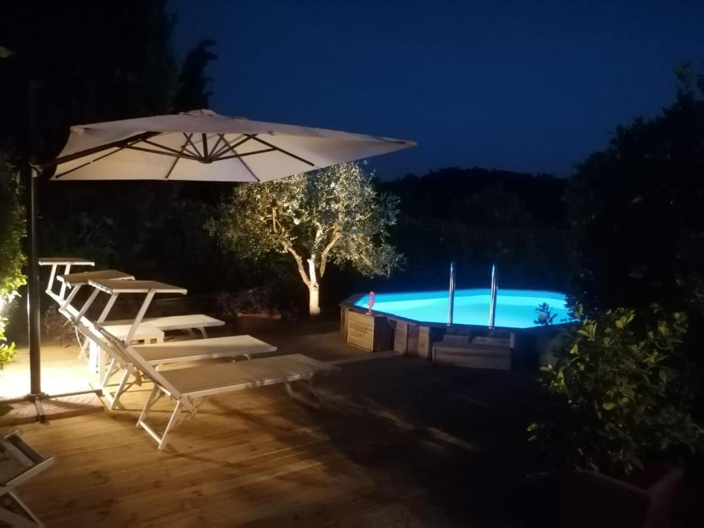 einen Pool mit einem Sonnenschirm und Stühlen sowie einem Pool in der Unterkunft Casa Vacanze "La Farfalla" in San Miniato