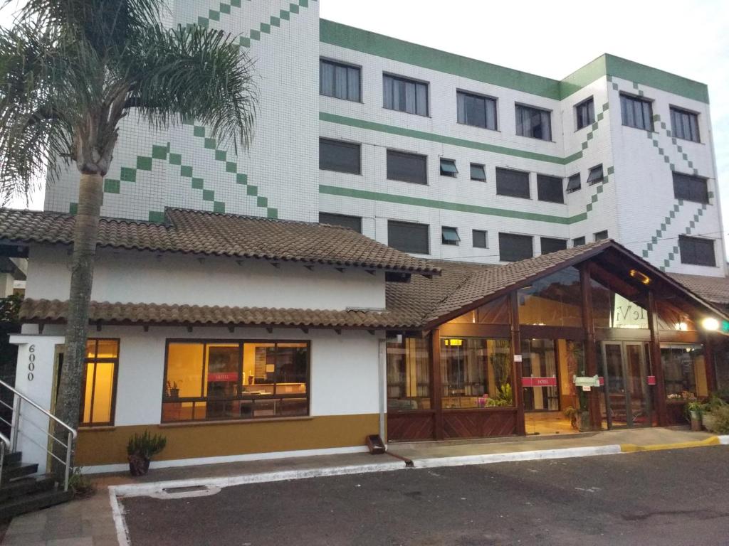 a building with a palm tree in front of it at Hotel Bemtevi in Farroupilha