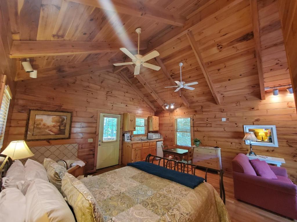 a bedroom in a log cabin with a bed and a couch at New River Trail Cabins in Galax