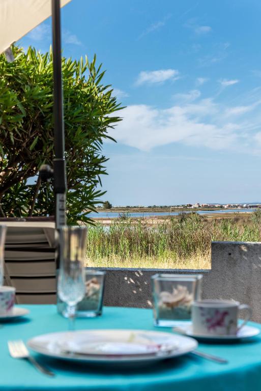une table avec un chiffon de table bleu avec des assiettes et des verres dans l'établissement Maisonеtte Arcadia - vue sur l'étang, à Gruissan