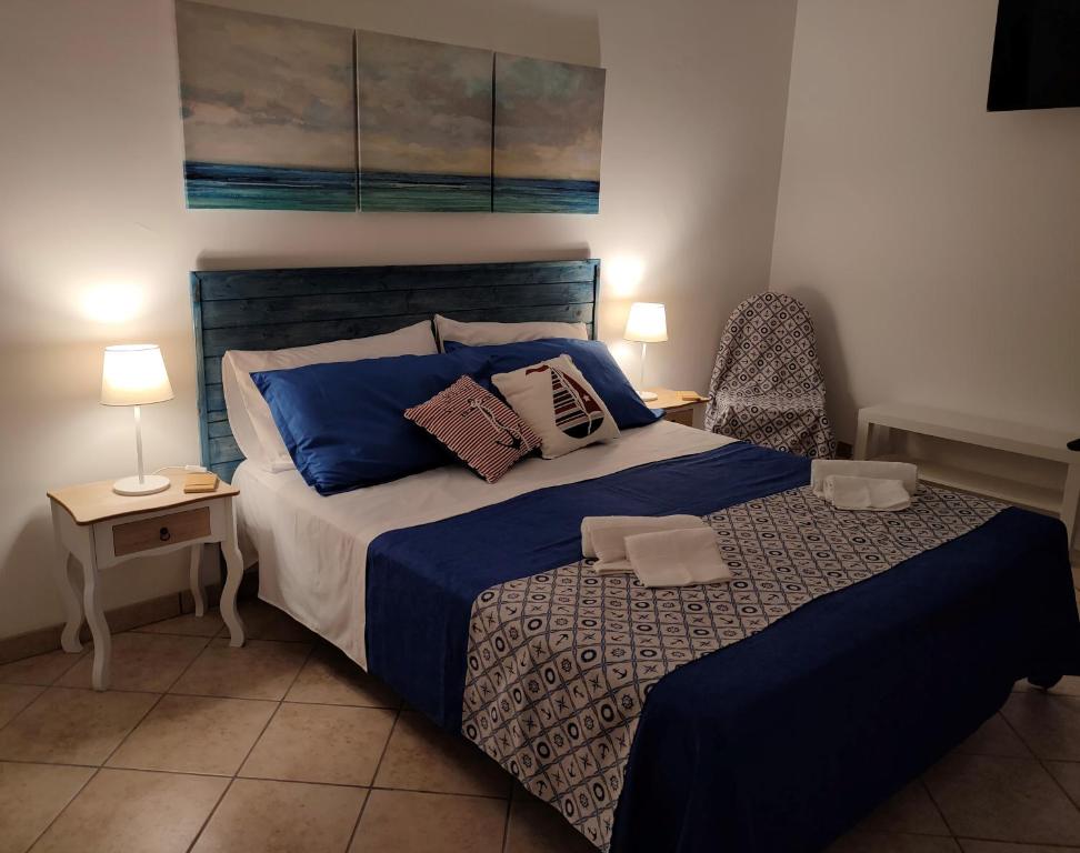 1 dormitorio con 1 cama grande con sábanas y almohadas azules en L'Ancora Blu, en Marina di Modica