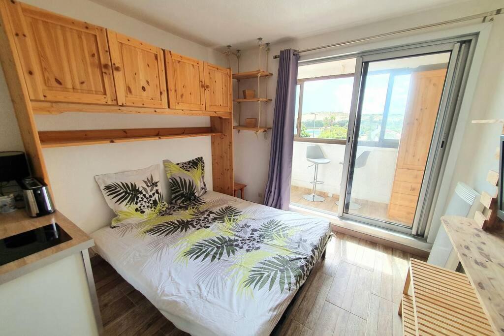 um pequeno quarto com uma cama e uma grande janela em Très charmant studio Plage du Penon em Seignosse