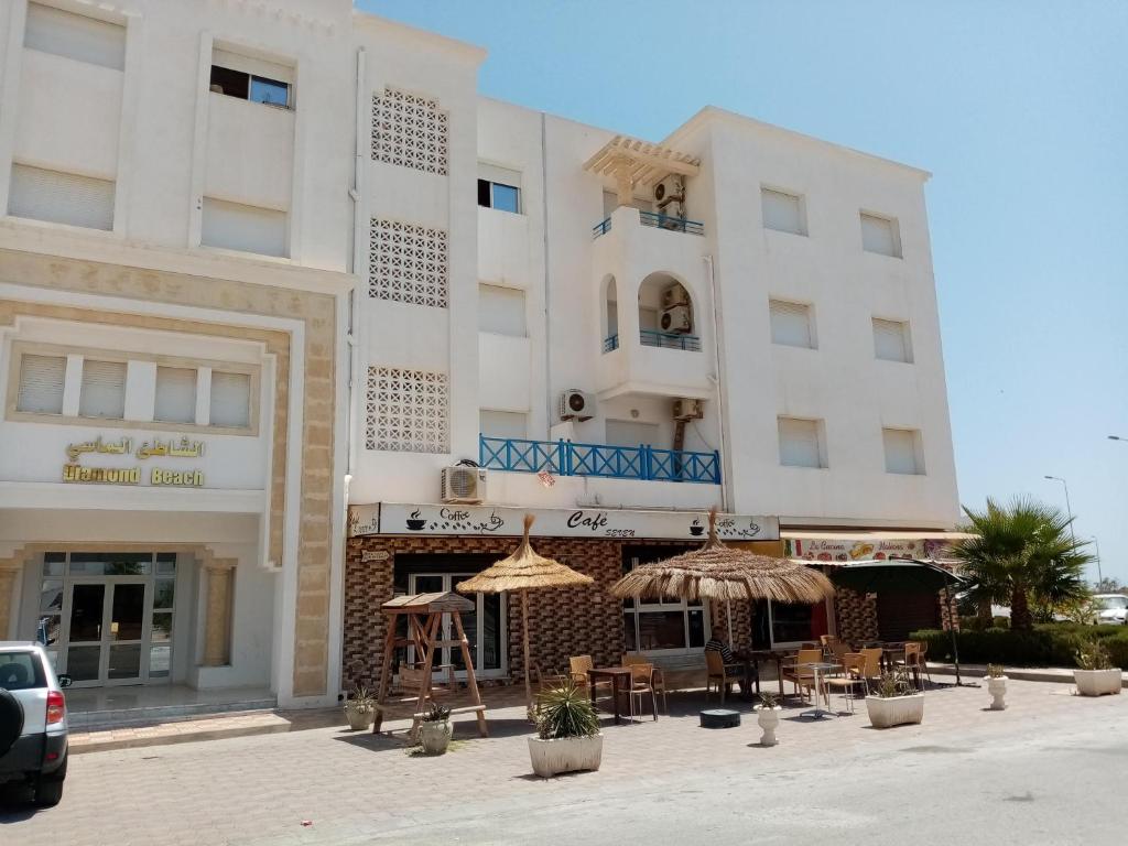 un bâtiment avec des tables et des parasols devant lui dans l'établissement Hergla_AFH_Beach, à Harqalah