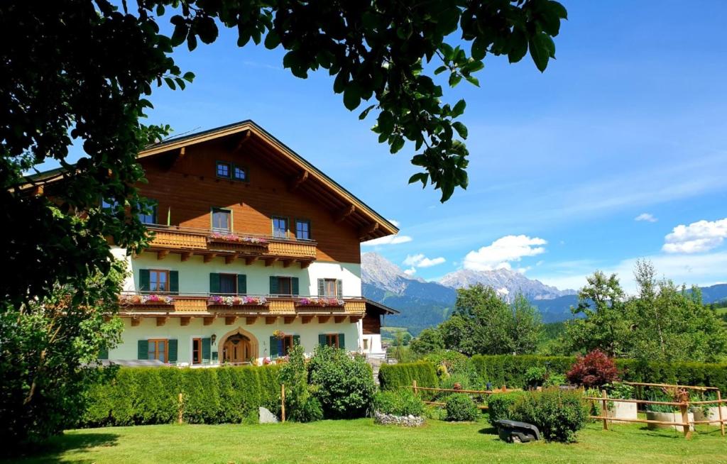 una casa en un campo con montañas en el fondo en Unterbiberghof, en Saalfelden am Steinernen Meer