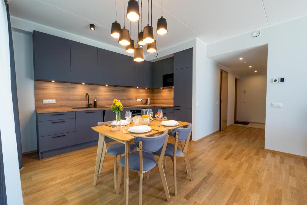 a kitchen with a wooden table and blue cabinets at Delta Luxury Apartment with terrace in Tartu