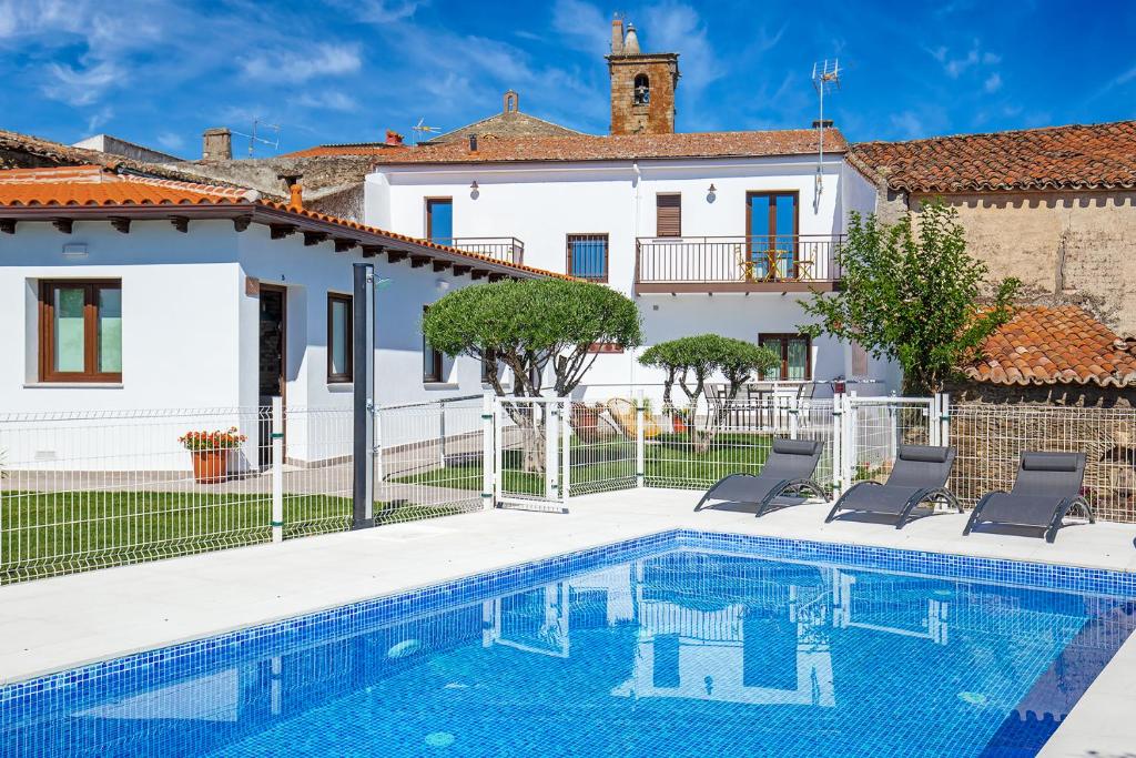 a villa with a swimming pool in front of a house at Apartamentos Rurales Cielo de Monfragüe in Malpartida de Plasencia