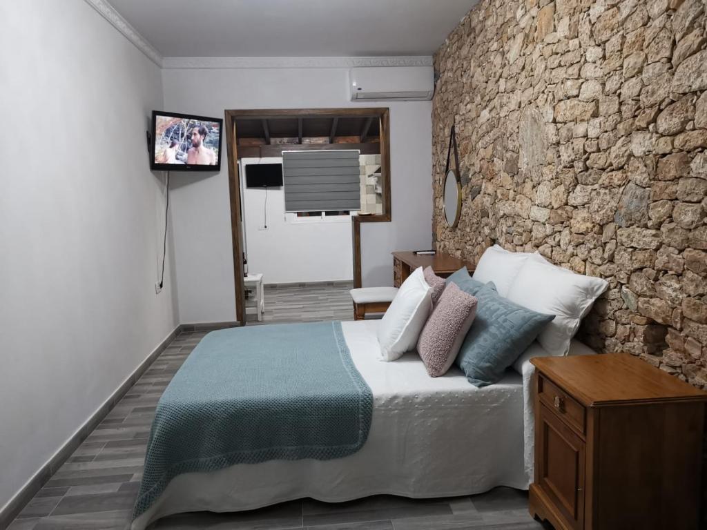 ein Schlafzimmer mit einem Bett und einer Steinmauer in der Unterkunft Adeyu Tropical in Tarajalejo