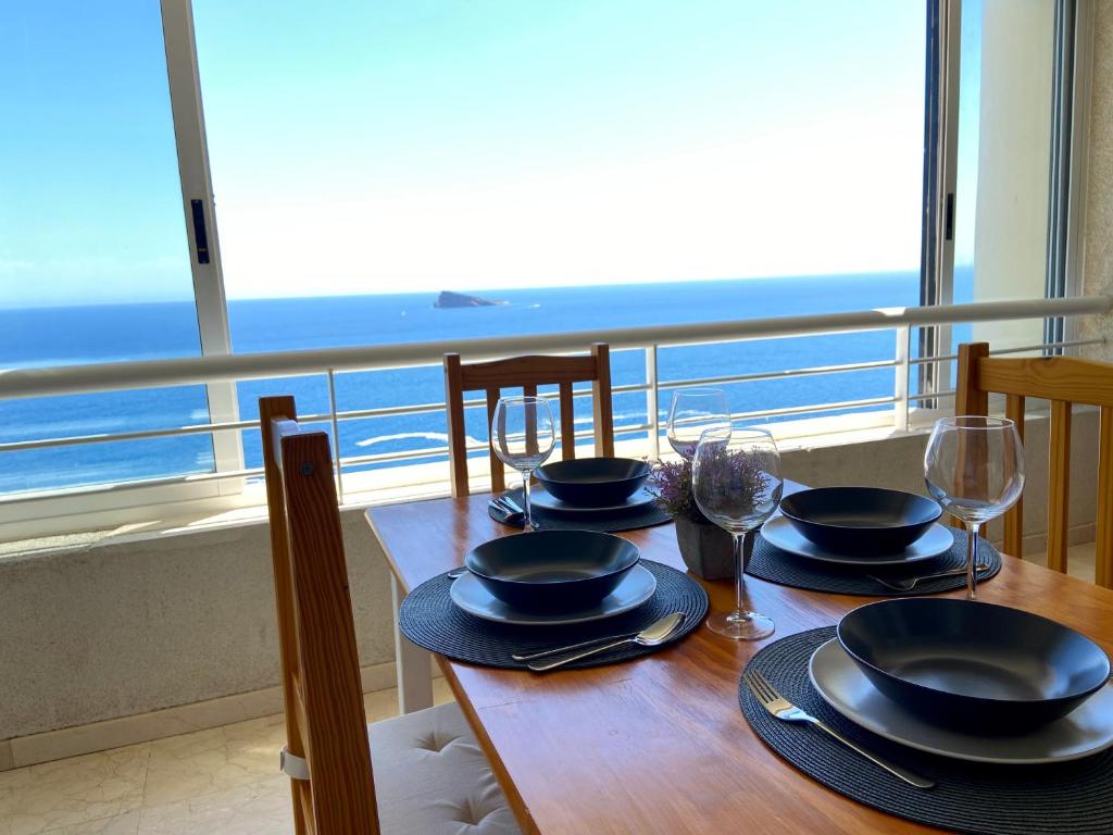 una mesa con sillas, platos y copas de vino en Apartamento Torre Levante, primera línea de playa, en Benidorm