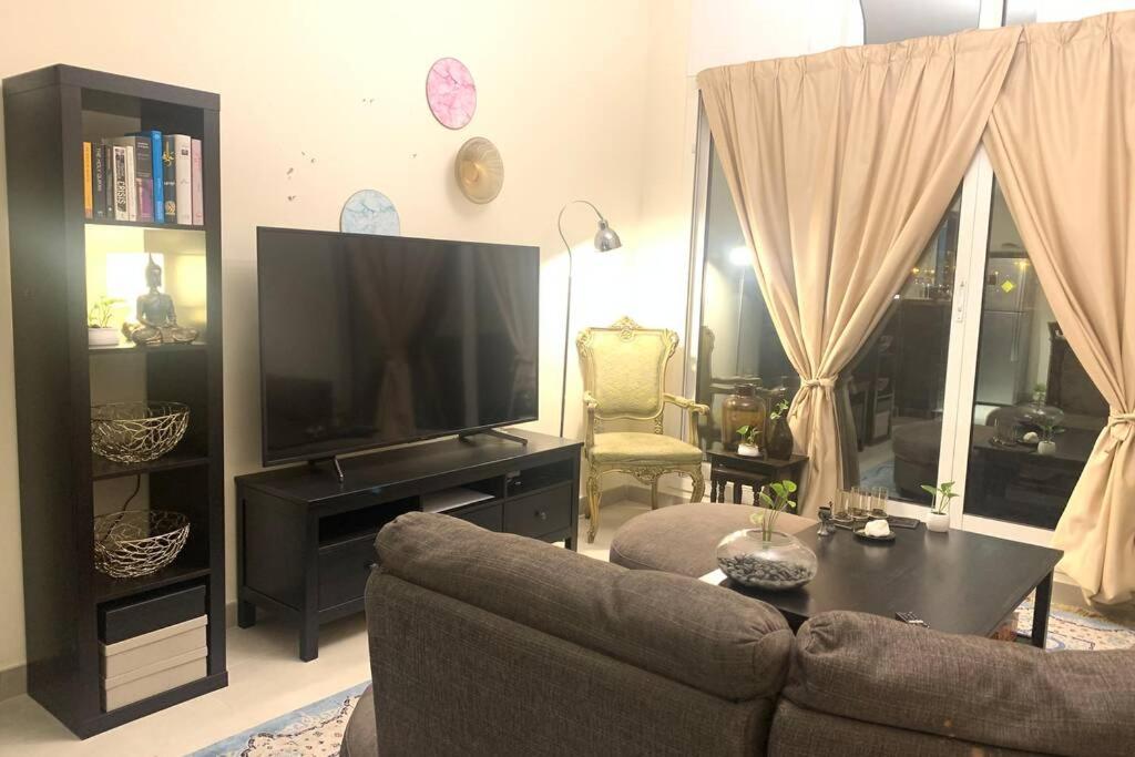 a living room with a couch and a flat screen tv at All inclusive 1 Bed room apartment - Airport road in Dubai