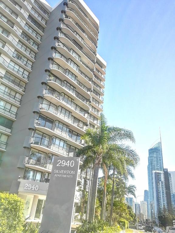 a tall building with a palm tree in front of it at Silverton Apartment Resort Surfers Paradise in Gold Coast