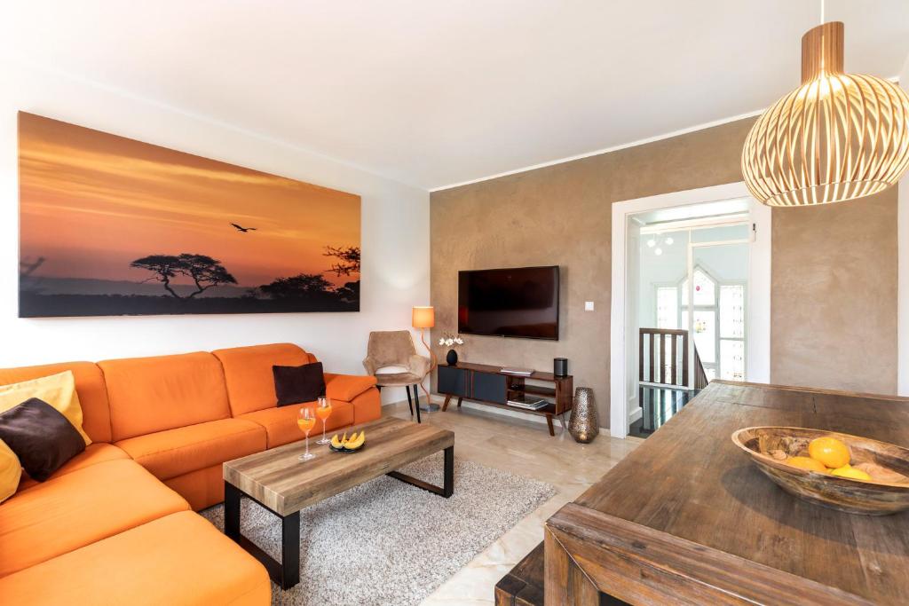 a living room with an orange couch and a table at PRIMERA Villa in Singen