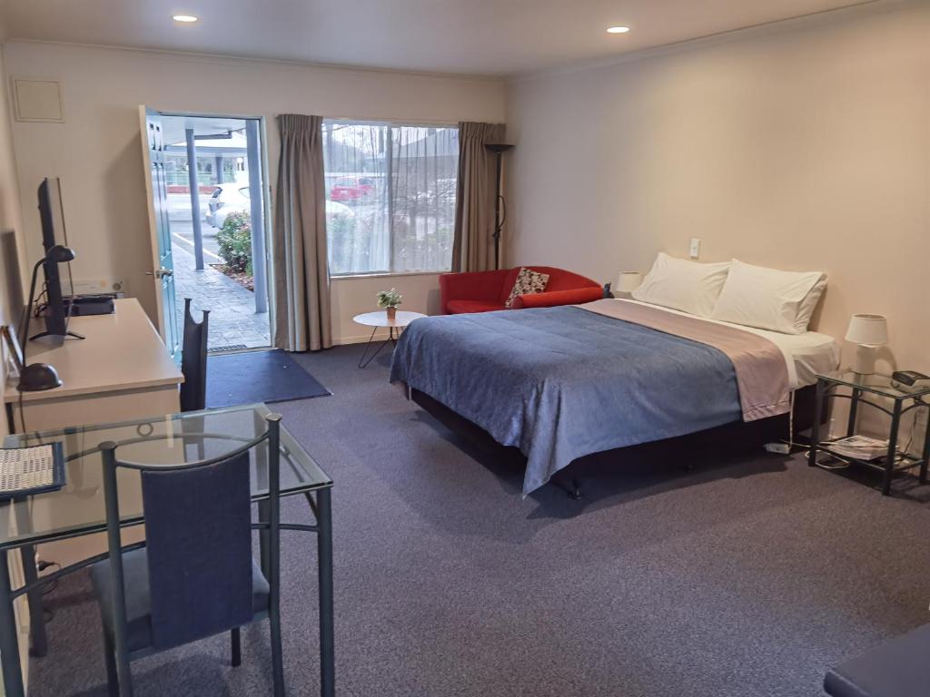 a bedroom with a bed and a table and a window at Harringtons Motor Lodge in Palmerston North