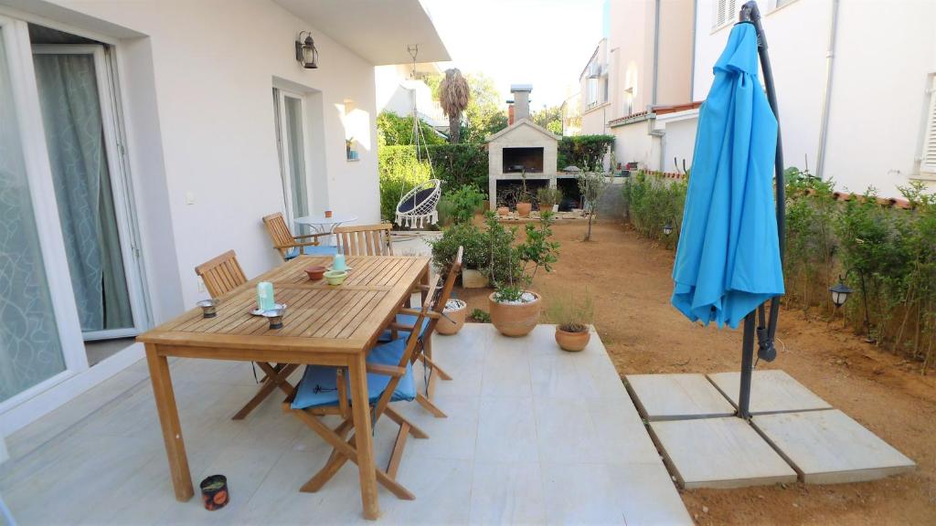 a patio with a wooden table and a blue umbrella at The Duke in Šibenik