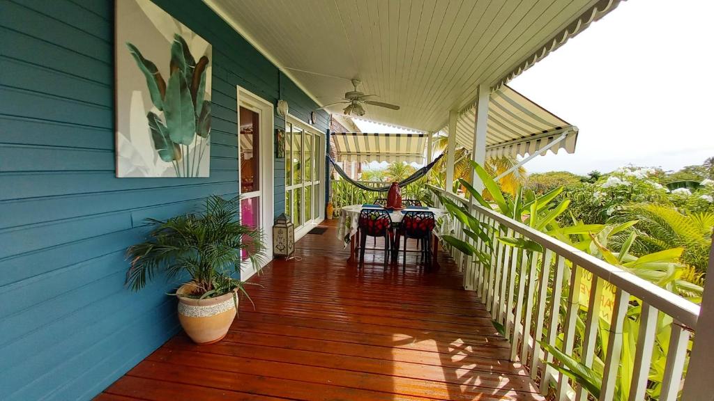 un porche de una casa azul con mesa y sillas en Bungalow de 2 chambres a Bouillante a 100 m de la plage avec vue sur la mer jardin amenage et wifi, en Bouillante