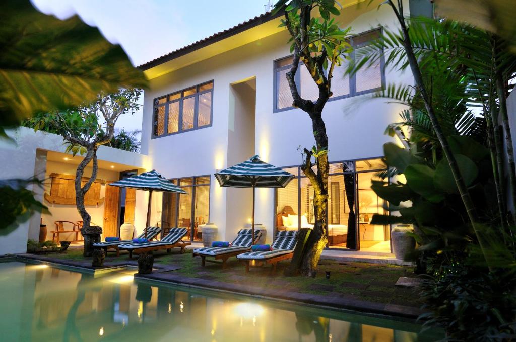 a villa with a swimming pool at night at Room & Vespa 1 in Seminyak