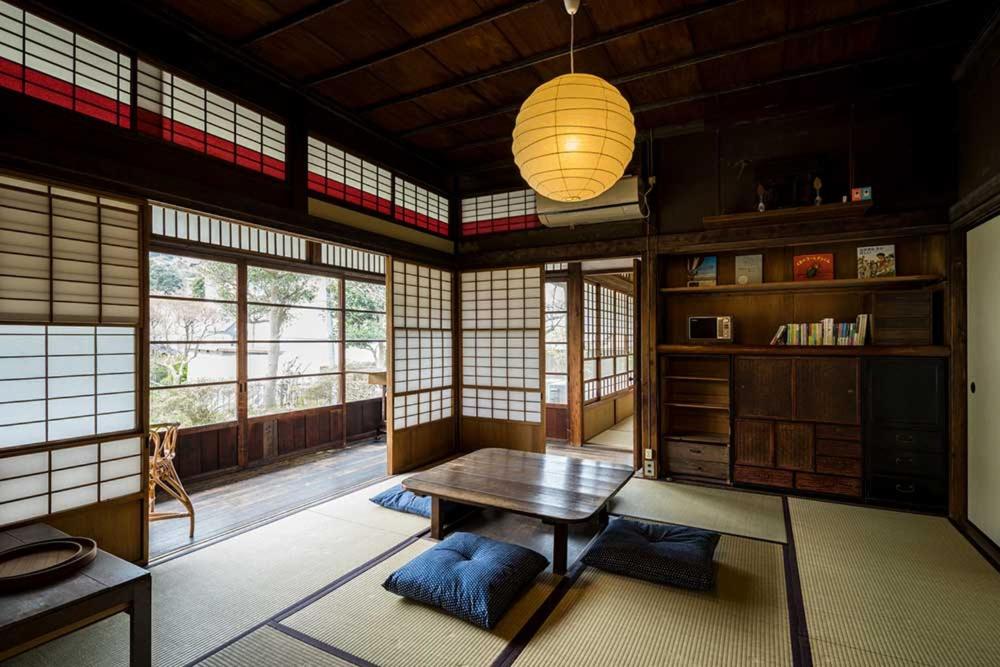 um quarto com uma mesa num quarto com janelas em 平野邸 Hayama em Hayama