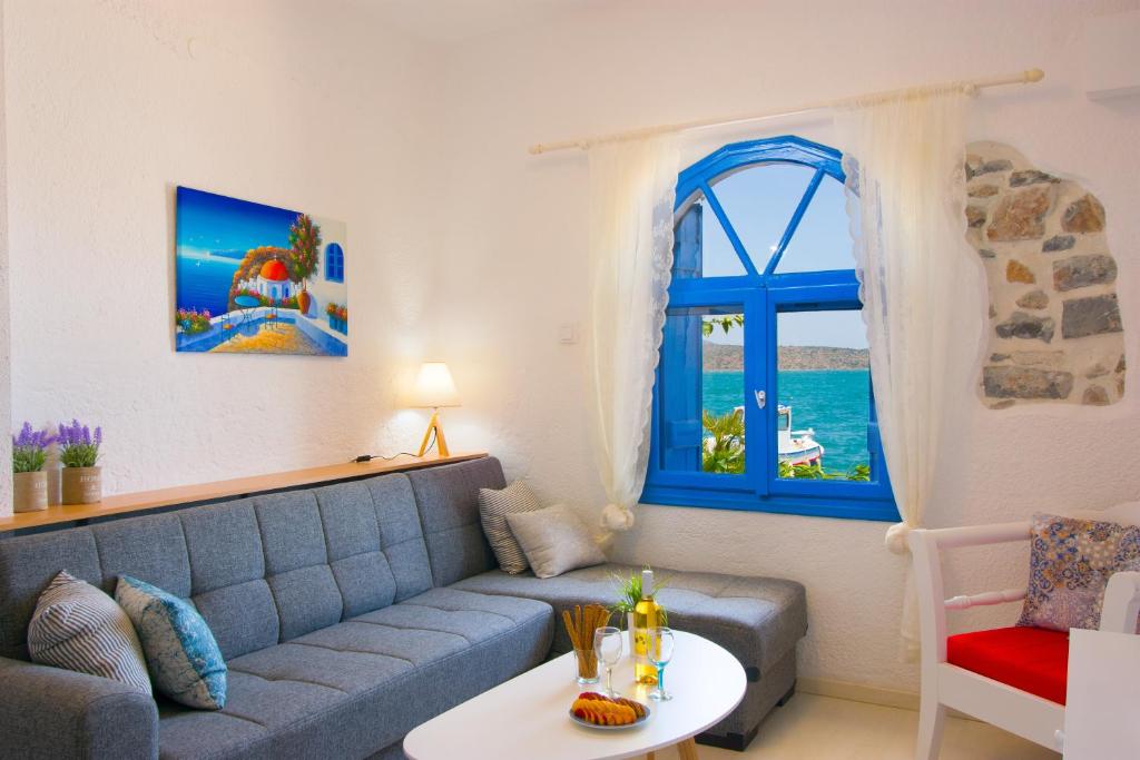 a living room with a blue couch and a window at Eleftheria Sea Side Traditional House in Elounda