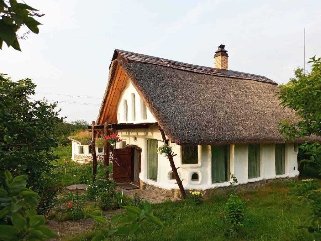 ein kleines weißes Cottage mit einem Strohdach in der Unterkunft Сказочный Дом (Fairy House) in Buki