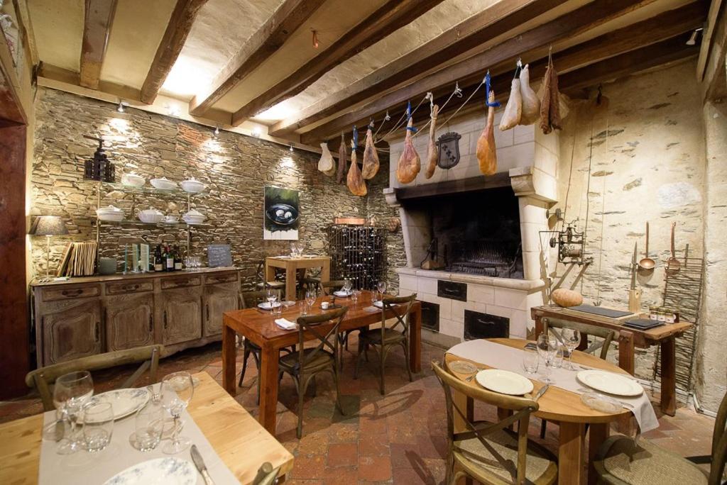 ein Esszimmer mit Holztischen und eine Küche in der Unterkunft L'Hotellerie de la Toile à Beurre in Ancenis