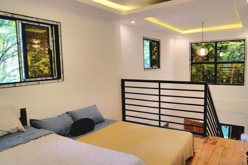 a bedroom with two beds and two windows at Purple Orchid Bed and Breakfast in Tagaytay