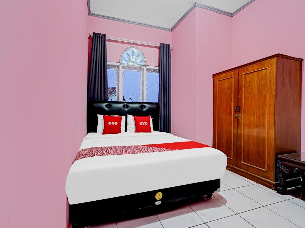 una camera rosa con letto con cuscini rossi di OYO 90289 Lestari Syariah Homestay a Cirebon