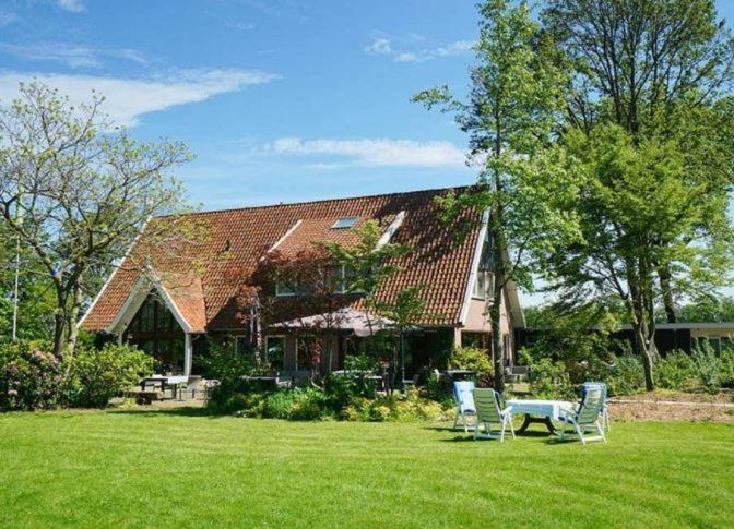 a house with chairs and a table in the yard at Bed&Breakfast hotel de Greune Weide in Eibergen